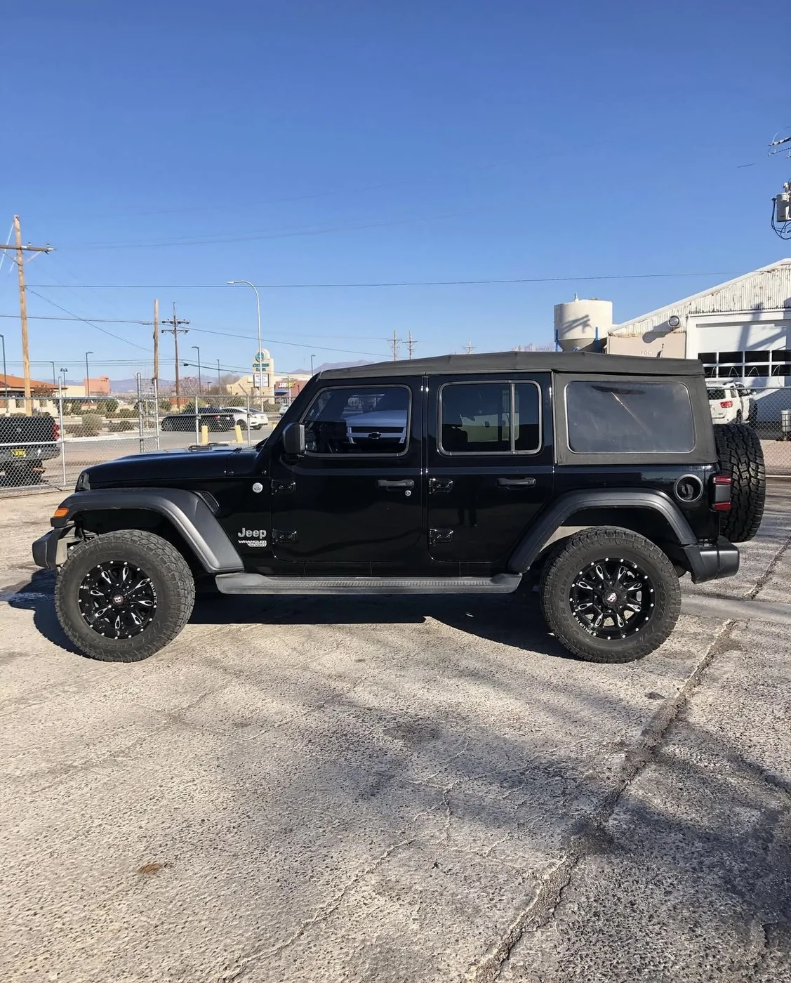 Black Jeep Wrangler Unlimited with aftermarket black wheels and all-terrain tires at Limitless Motorsports in Las Cruces, NM
