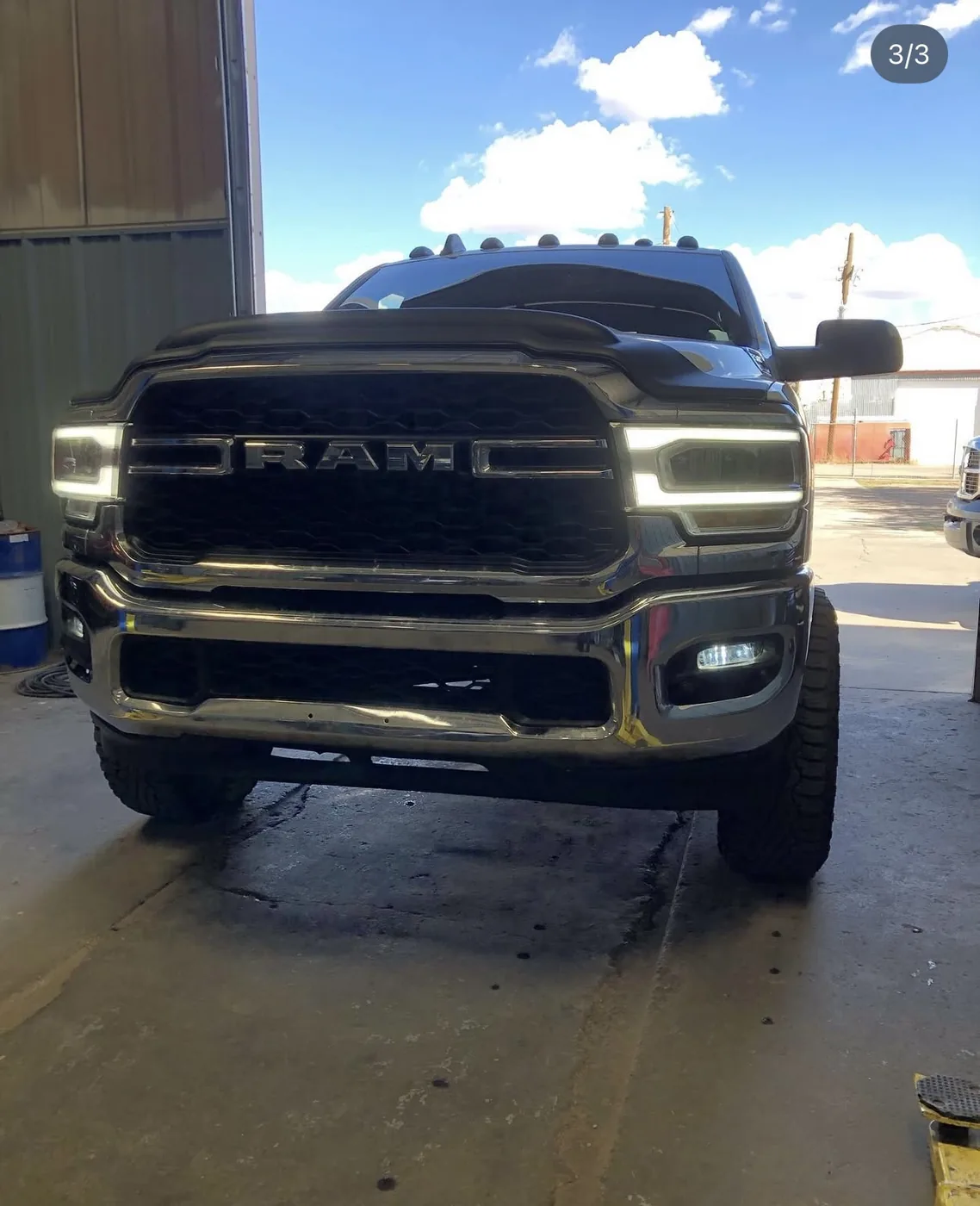 Lifted black Ram 2500 Heavy Duty with cab roof lights and off-road tires in the Limitless Motorsports service bay